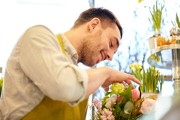 Image showing smiling florist man making bunch at flower shop