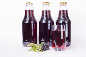 Image showing Bottles of syrup made from chokeberry and glass