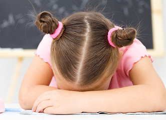 Image showing Little girl is sleeping on her writing-book