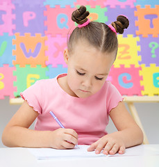 Image showing Little girl is writing using a pen