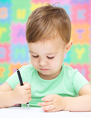 Image showing Little boy is writing on his copybook