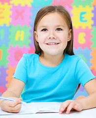 Image showing Little girl is writing using a pen