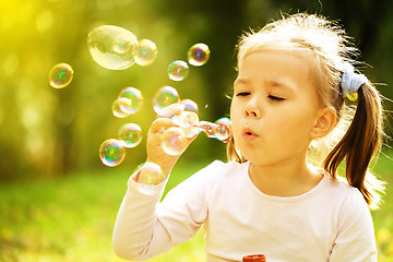 Image showing Little girl is blowing a soap bubbles