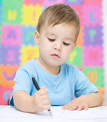 Image showing Little boy is writing on his copybook