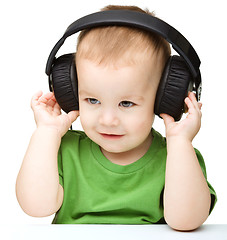 Image showing Cute little boy enjoying music using headphones