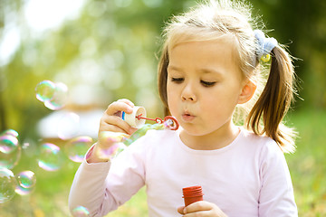 Image showing Little girl is blowing a soap bubbles