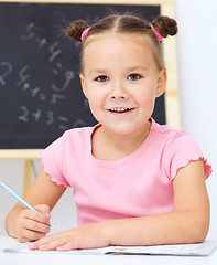 Image showing Little girl is writing using a pen