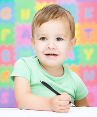 Image showing Little boy is writing on his copybook