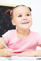 Image showing Little girl is writing using a pen