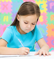 Image showing Little girl is writing using a pen