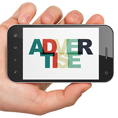 Image showing Advertising concept: Hand Holding Smartphone with Advertise on  display