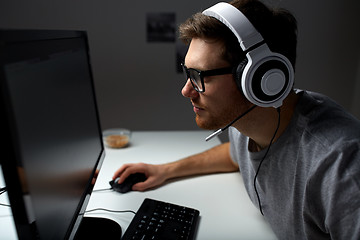 Image showing man in headset playing computer video game at home