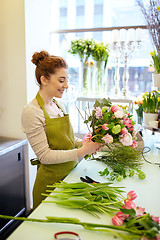 Image showing smiling florist woman making bunch at flower shop