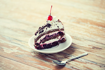 Image showing piece of cherry chocolate cake on wooden table