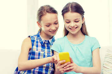 Image showing happy girls with smartphone sitting on sofa