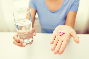 Image showing close up of woman hands with pills and water