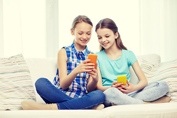 Image showing happy girls with smartphones sitting on sofa