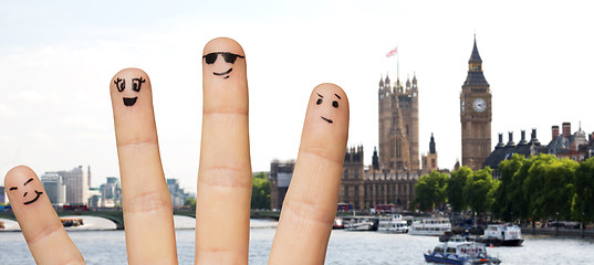 Image showing close up of fingers with smiley faces over london