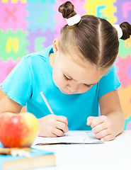 Image showing Little girl is writing using a pen