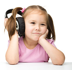 Image showing Cute little girl is bored to listen music