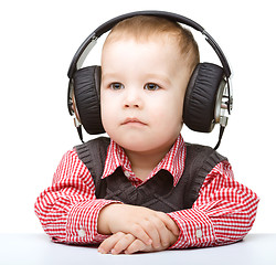 Image showing Cute little boy enjoying music using headphones