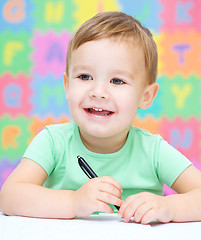 Image showing Little boy is writing on his copybook