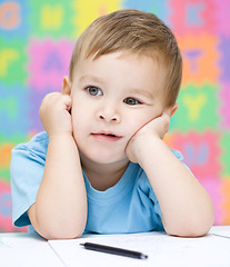 Image showing Little boy is writing on his copybook