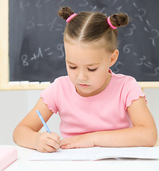 Image showing Little girl is writing using a pen