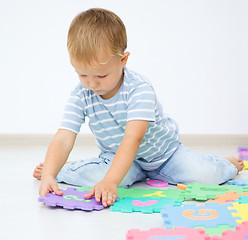 Image showing Little boy is putting together a big puzzle