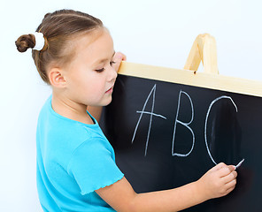 Image showing Little girl is writing on a blackboard