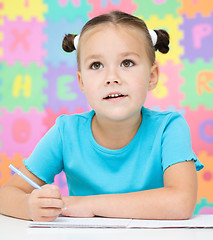 Image showing Little girl is writing using a pen