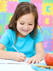 Image showing Little girl is writing using a pen