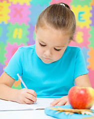 Image showing Little girl is writing using a pen