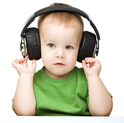 Image showing Cute little boy enjoying music using headphones