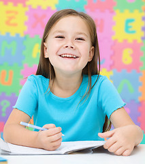 Image showing Little girl is writing using a pen