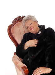 Image showing Senior woman sitting in pink armchair.