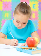 Image showing Little girl is writing using a pen