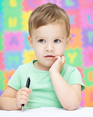 Image showing Little boy is writing on his copybook