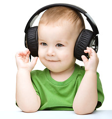 Image showing Cute little boy enjoying music using headphones