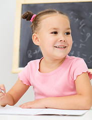 Image showing Little girl is writing using a pen