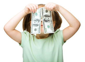 Image showing Little girl is covering her eyes with dollars