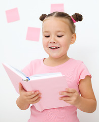 Image showing Little girl is reading a book