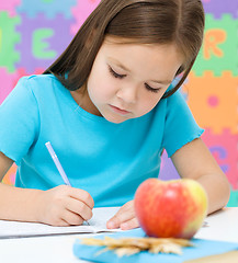 Image showing Little girl is writing using a pen