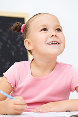 Image showing Little girl is writing using a pen