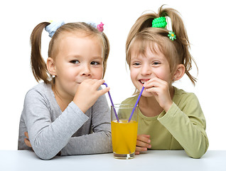 Image showing Two Little girls are drinking orange juice