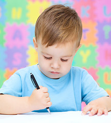 Image showing Little boy is writing on his copybook