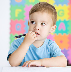 Image showing Little boy is writing on his copybook