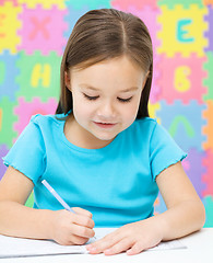 Image showing Little girl is writing using a pen