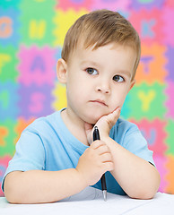 Image showing Little boy is writing on his copybook