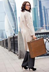 Image showing woman in a bright coat and a wooden case